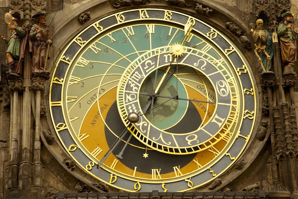 A detailed astronomical clock with Roman numerals and zodiac signs.