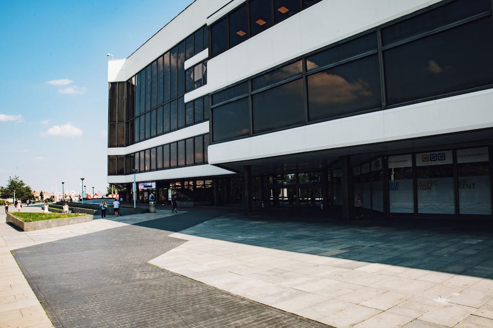 Un edificio moderno con ampie finestre e una piazza pavimentata.