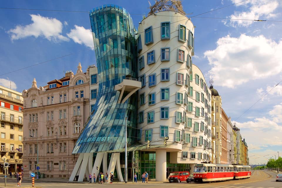 A modern building with a glass facade and a traditional building with green shutters.