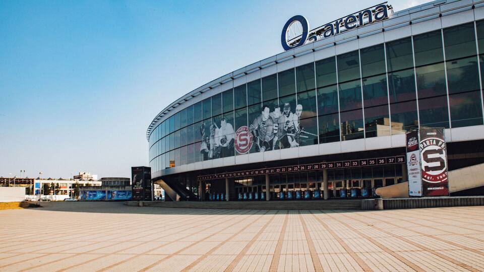 A modern stadium with a large glass facade and a prominent logo.