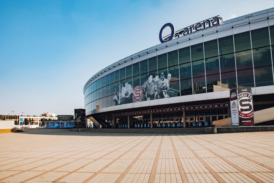 Uno stadio moderno con una vasta facciata vetrata e un logo ben visibile.