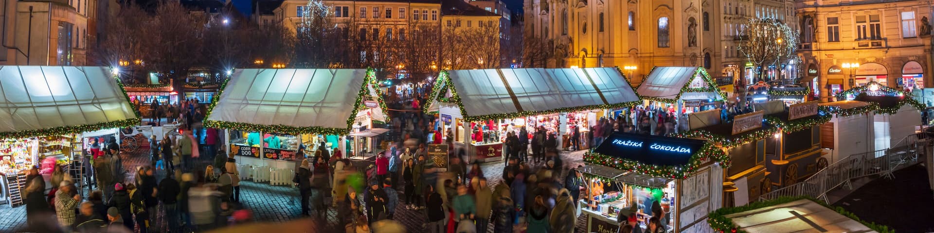 A bustling nighttime market with stalls and a prominent church in the background.