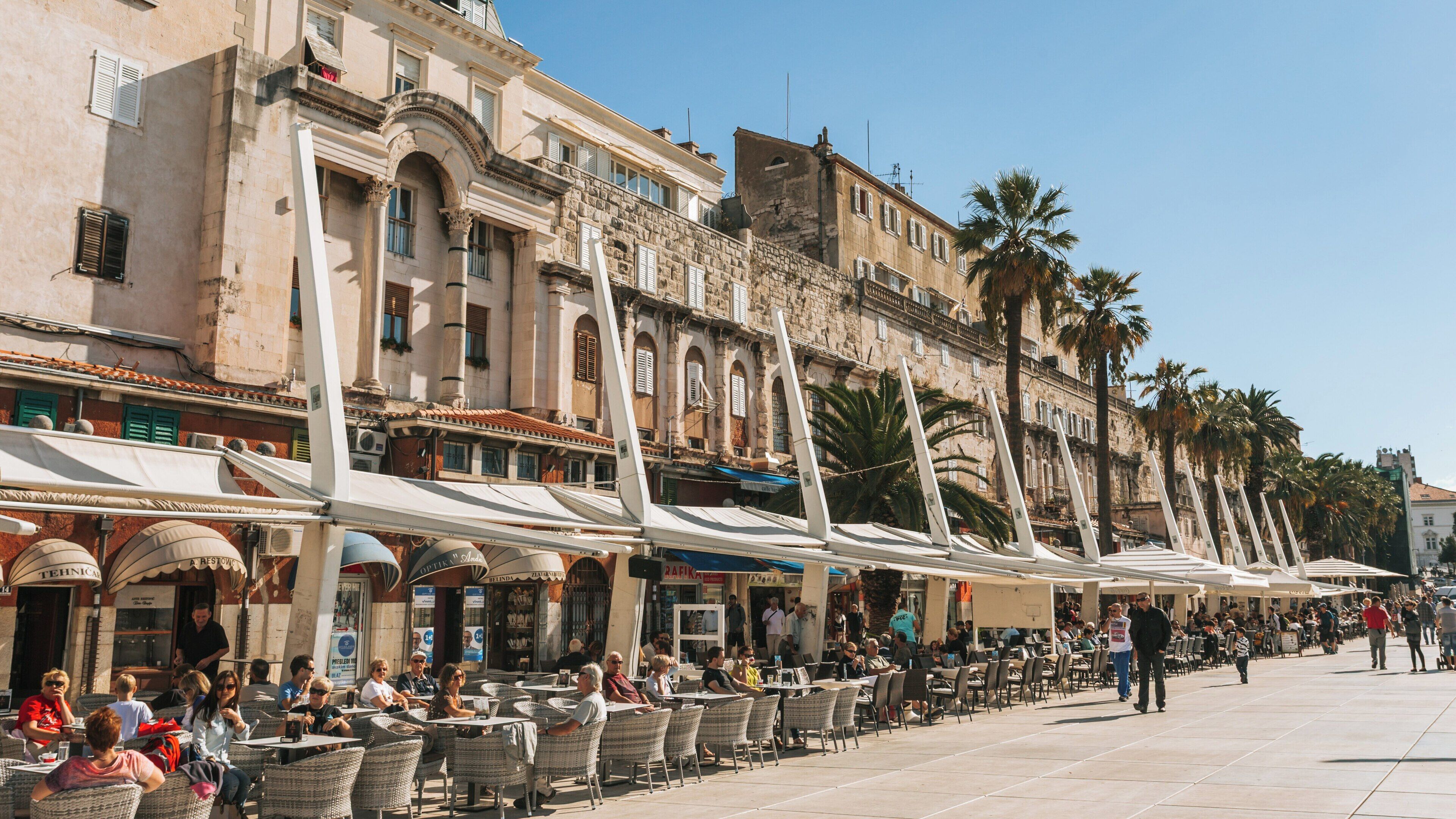 Visitors enjoy a sunny afternoon at Diocletian's Palace in Old Town Split, Croatia with vibrant cafes and historic architecture
