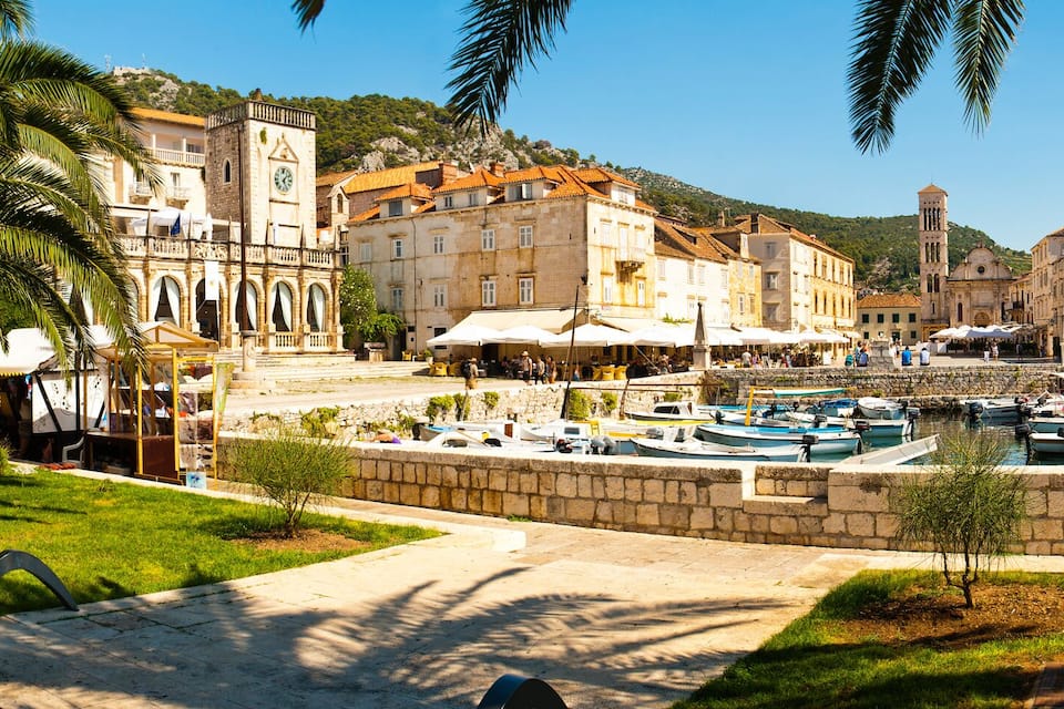 Un pueblo costero con edificios históricos, un puerto deportivo y palmeras.