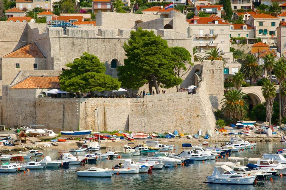 Un’antica fortezza in pietra con un porto pieno di imbarcazioni.