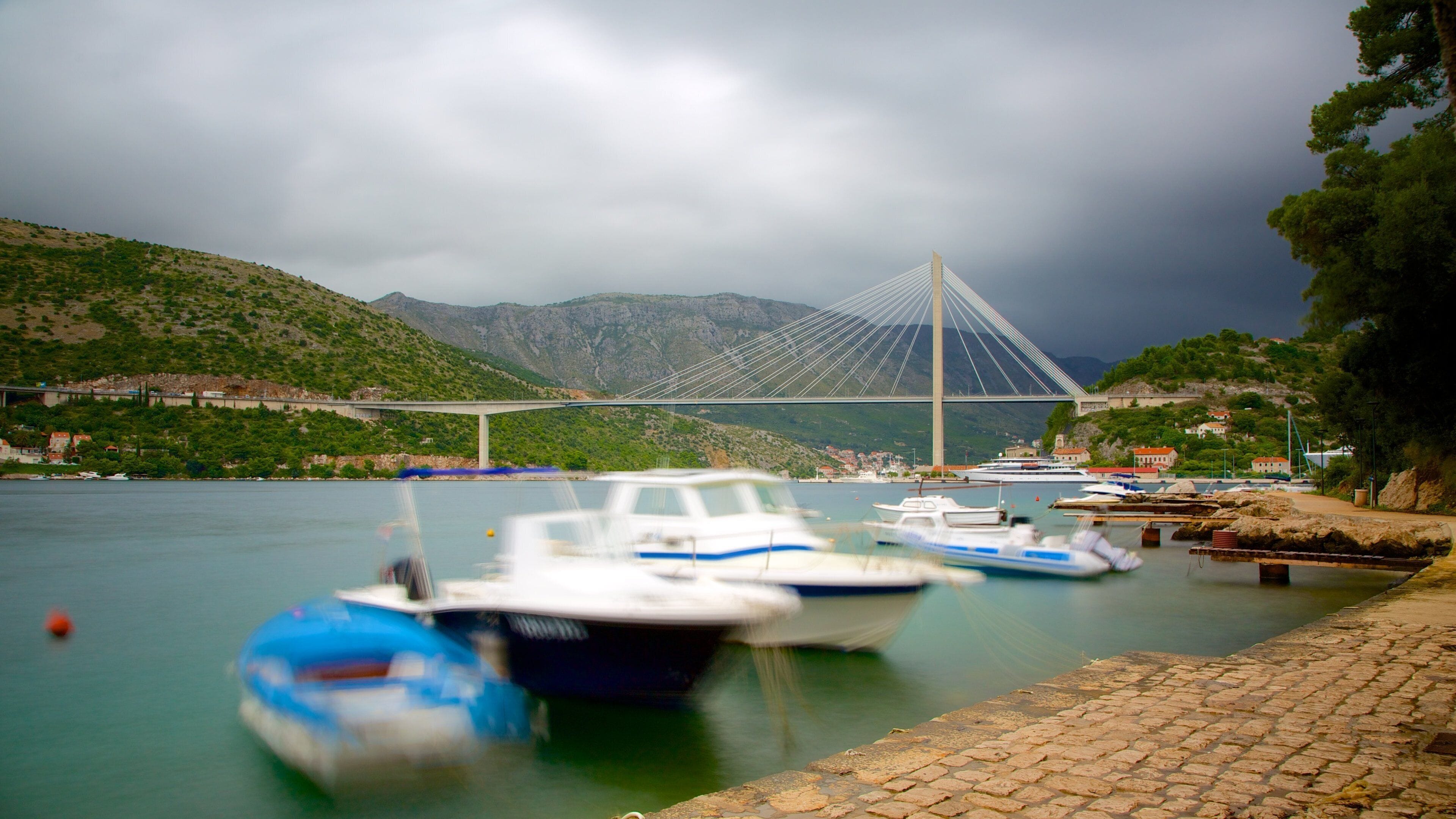 Lapad Beach featuring mountains, boating and a bridge