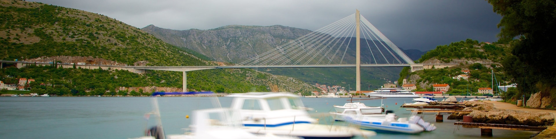 Un puente, barcos y un paisaje montañoso.