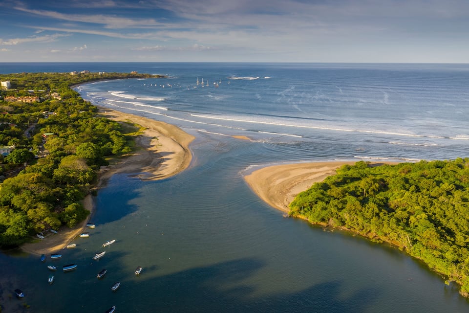 Un paysage côtier avec une plage, des bateaux et une végétation luxuriante.