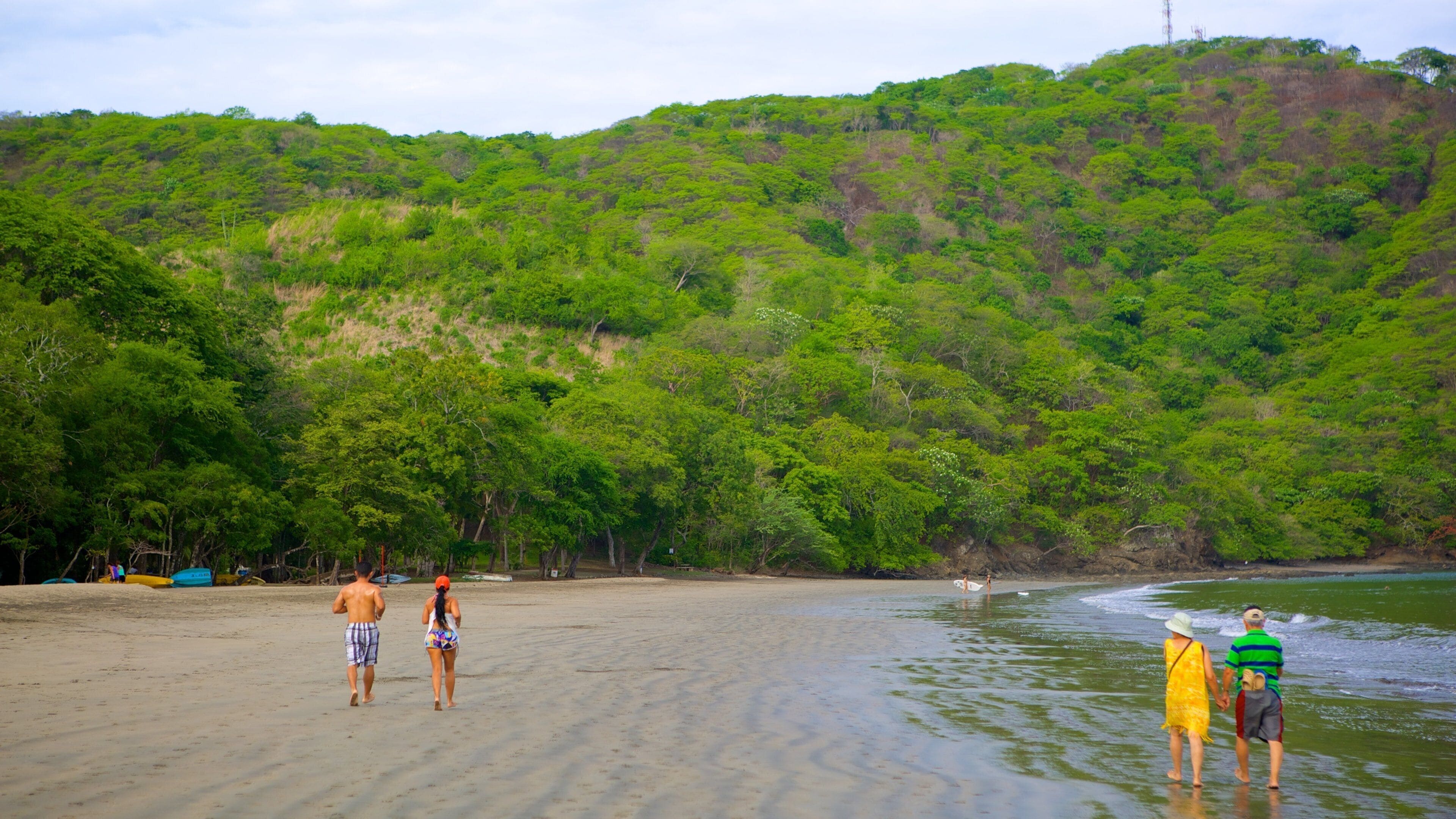 Playa de Bahía Hermosa mostrando una playa de arena y montañas y también un pequeño grupo de personas