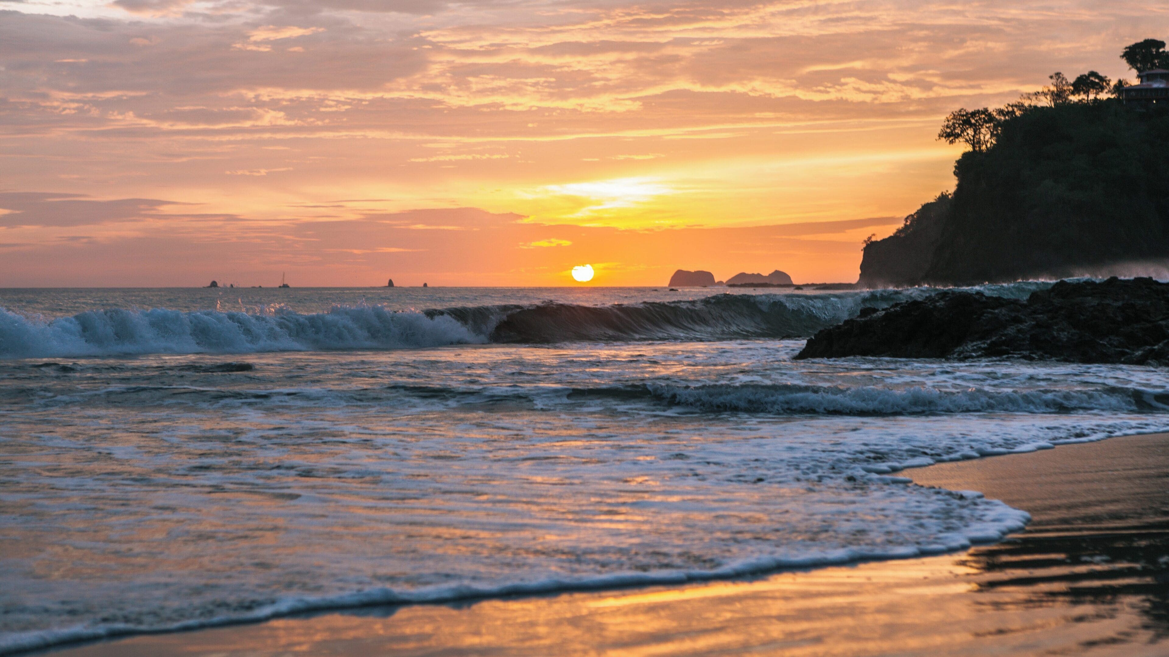 Beautiful sunset at Flamingo Beach in Potrero, Guanacaste, Costa Rica with gentle waves and distant rocky islands