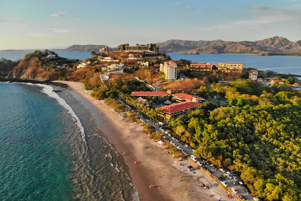 Une ville côtière dotée d’une plage, d’un grand ensemble d’immeubles et bordée de montagnes.
