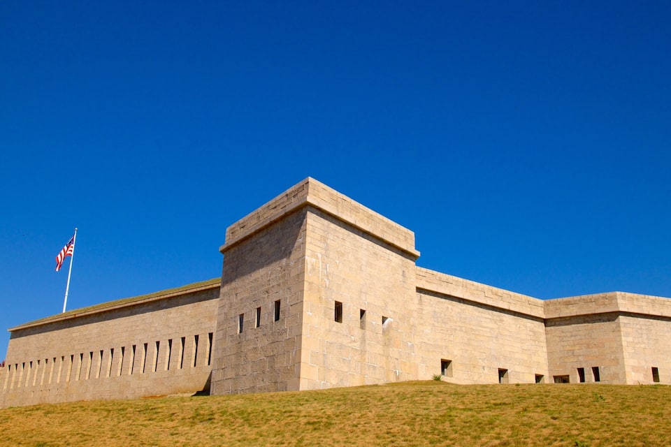 A large, rectangular stone building with a flat roof and a flagpole.