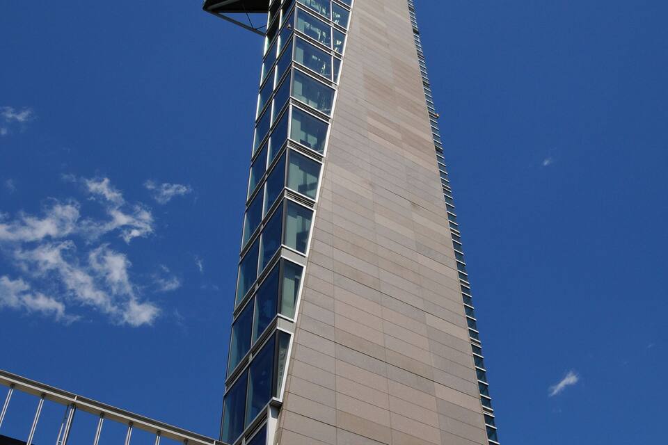 Um edifício alto com um design angular distinto e fachada de vidro.