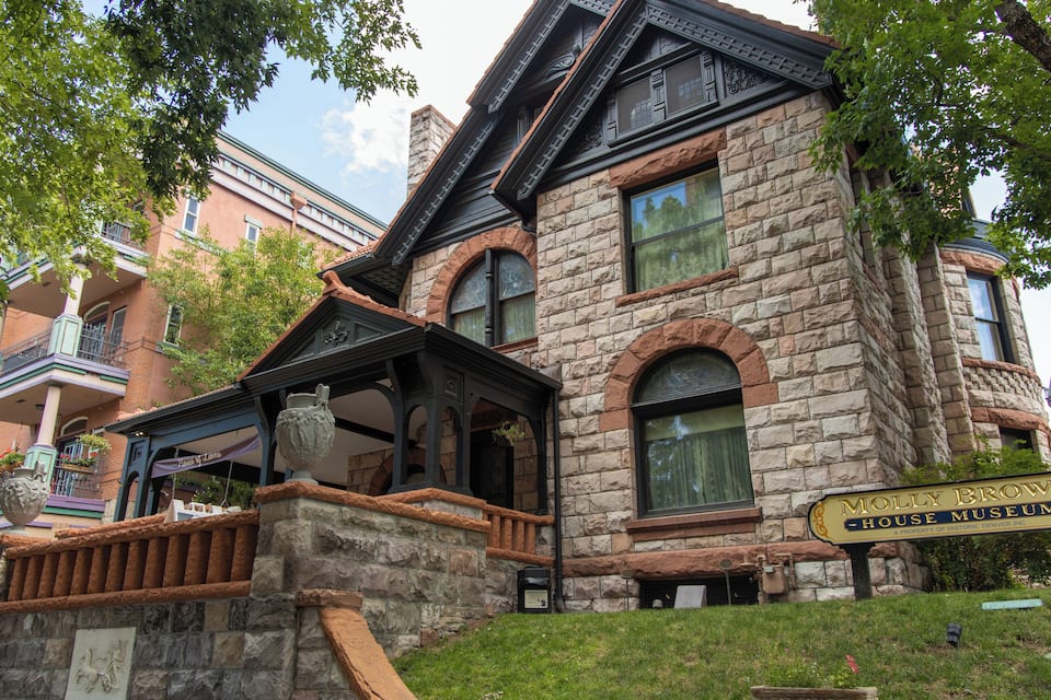 A historic house museum with stone walls, large windows, and a prominent sign.