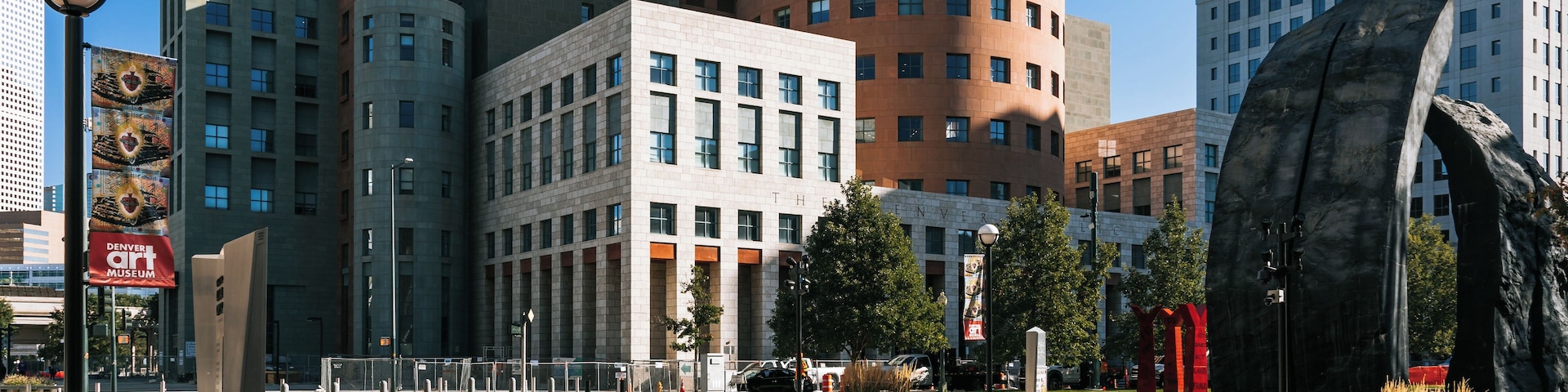 Eine moderne Stadtansicht mit verschiedenen Architekturstilen, darunter ein markantes Gebäude mit kreisförmigem Fundament und flachem Dach.