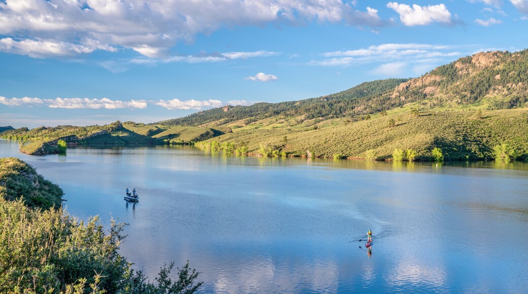 summer morning on Horsetooth Reservoir at foothills of Rocky Mountains in northern Colorado with a fishing boat and a stand up paddler, popular recreation destination in Fort Collins area