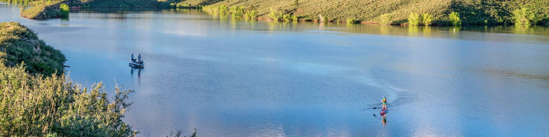 summer morning on Horsetooth Reservoir at foothills of Rocky Mountains in northern Colorado with a fishing boat and a stand up paddler, popular recreation destination in Fort Collins area