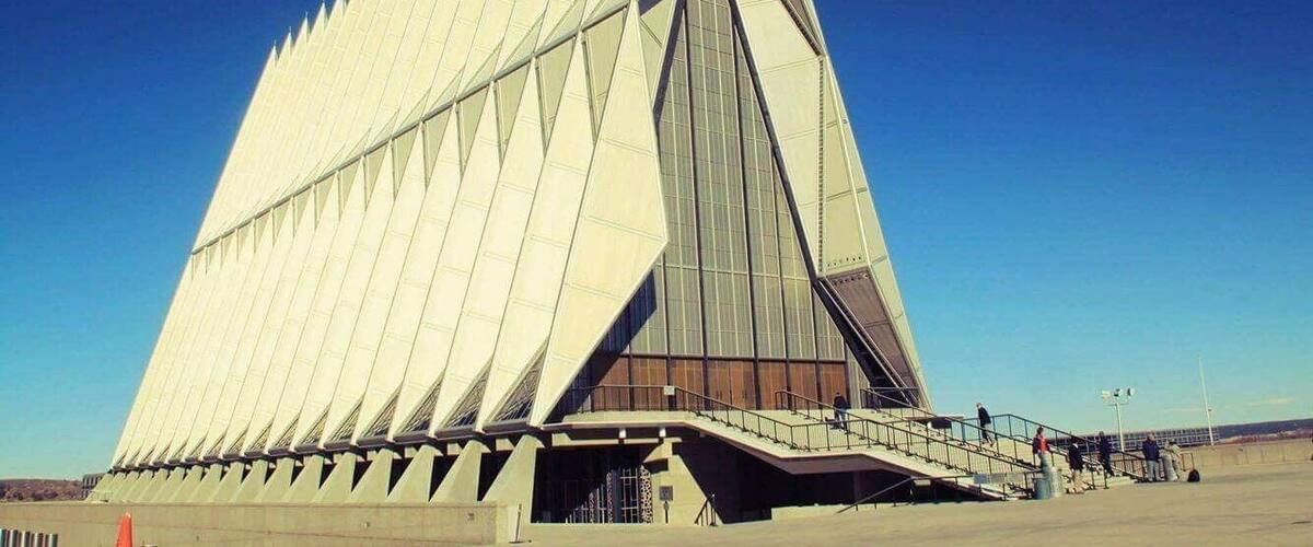 A modern architectural building with a triangular design and a large glass facade.