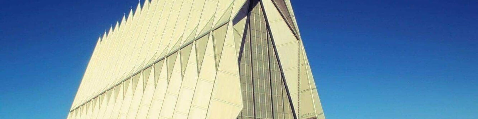 A modern architectural building with a triangular design and a large glass facade.
