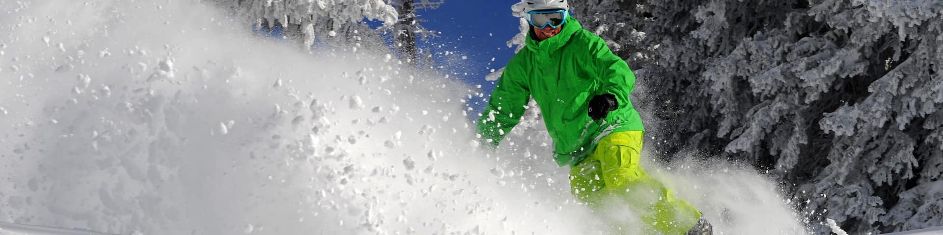 A person snowboarding down a snowy slope with trees in the background.