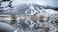 A snow-covered mountain, a lake, and a building in the background.