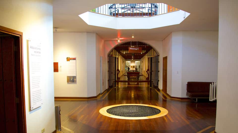 Um corredor com piso de madeira, claraboia e escada que leva a um andar superior.