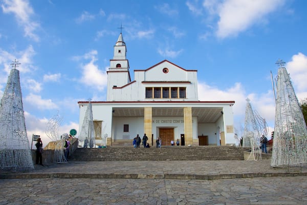 Uma igreja com um campanário e duas grandes árvores de Natal na frente.