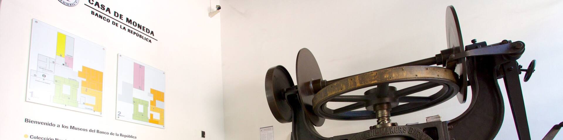A mechanical device, possibly a historical artifact, in a museum setting with informational posters on the wall.