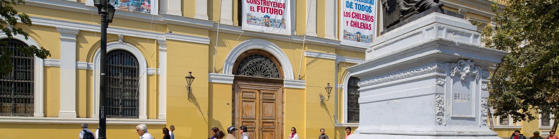Universidade do Chile que inclui uma estátua ou escultura e cenas de rua assim como um grande grupo de pessoas