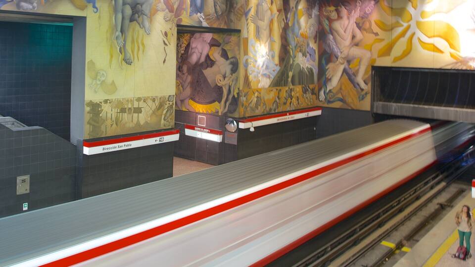 A subway station with a mural on the wall and a train on the platform.