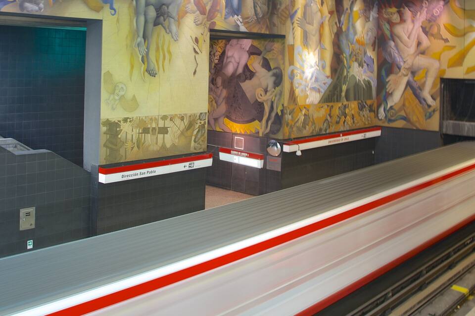 Een metrostation met een muurschildering en een trein op het perron.