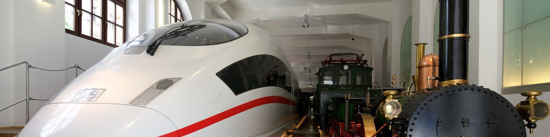 Un tren bala moderno y una locomotora de vapor antigua en un museo.