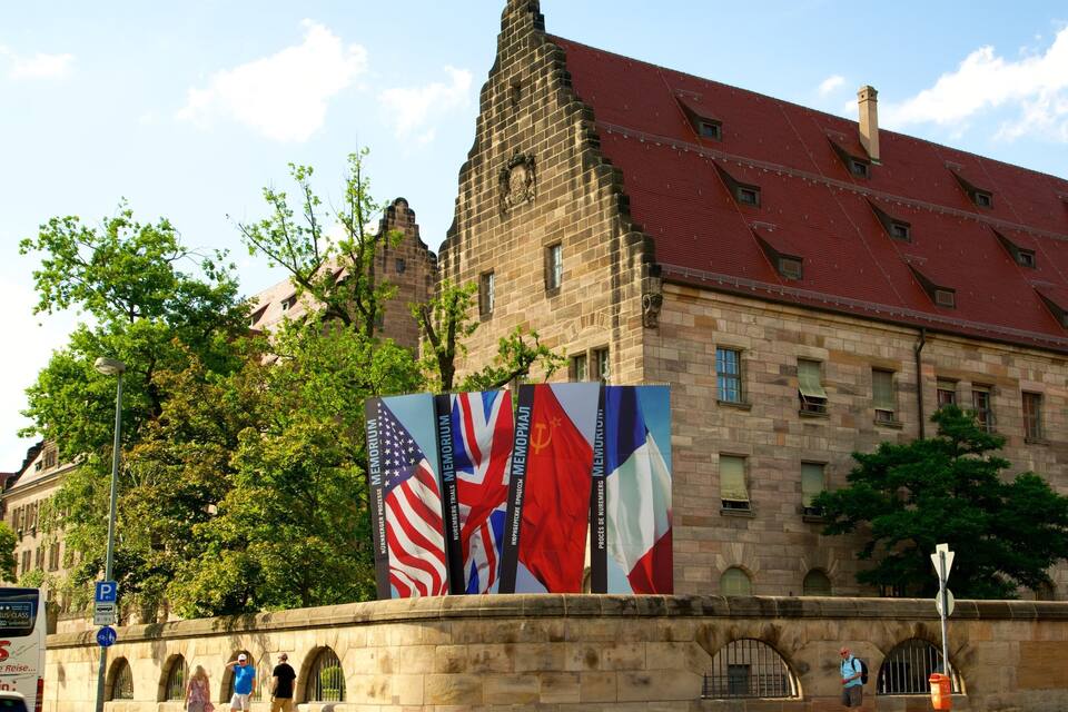 A historic building with a red roof and stone walls, featuring a large mural of flags.