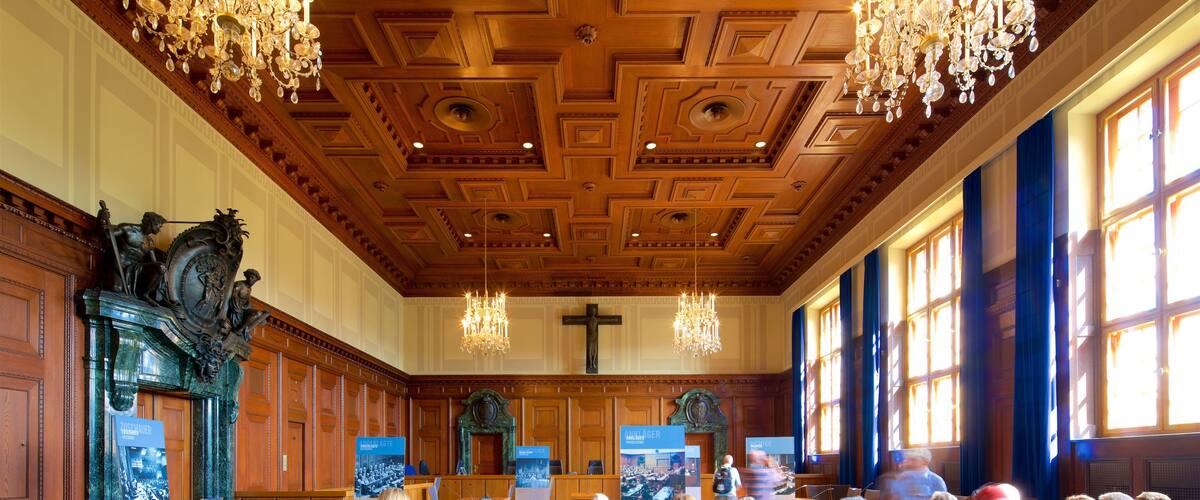 A church interior with wooden pews, a wooden ceiling with intricate patterns, and a large cross.