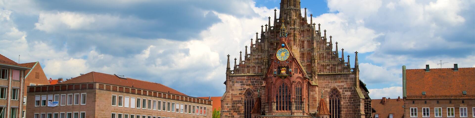 A historic church with a clock tower, surrounded by red and white striped market stalls.