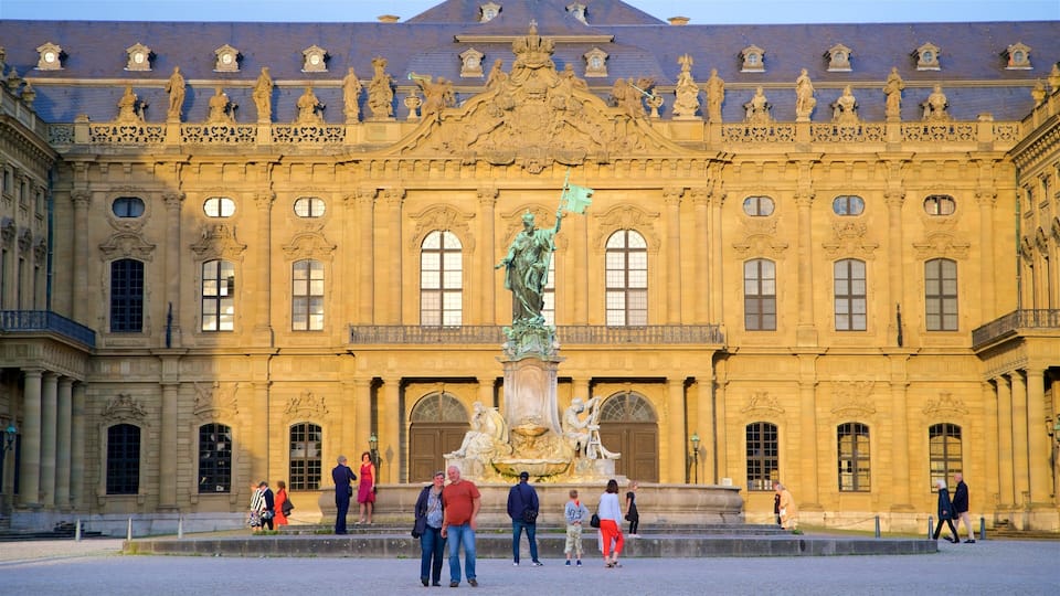 A grand building with ornate sculptures and statues, a large fountain, and people walking around.