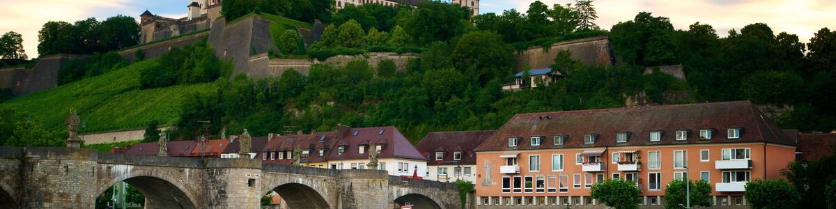 A historic castle on a hill, a stone bridge, and residential buildings along a river.