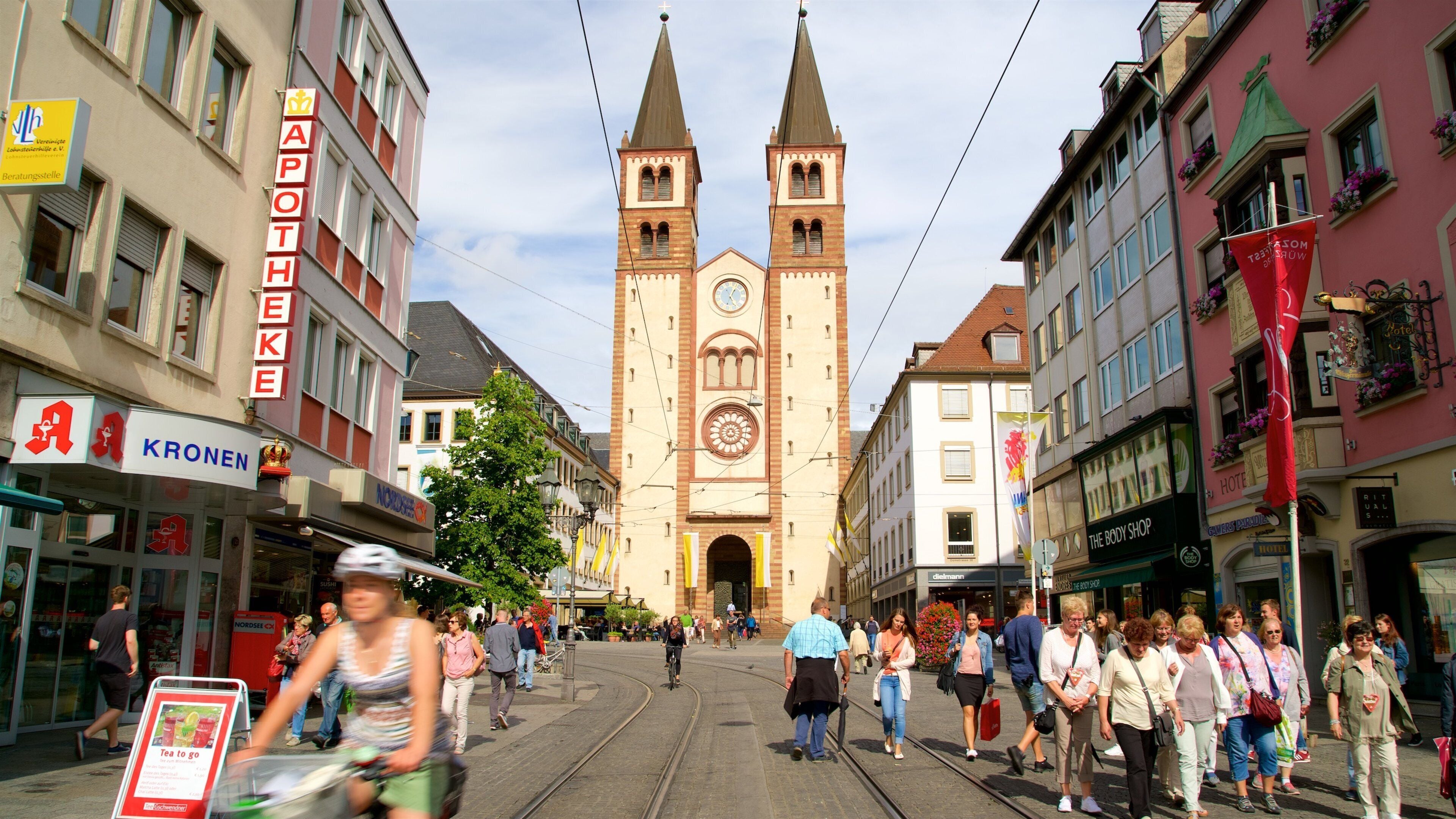 A bustling street with a prominent church tower, shops, and pedestrians.