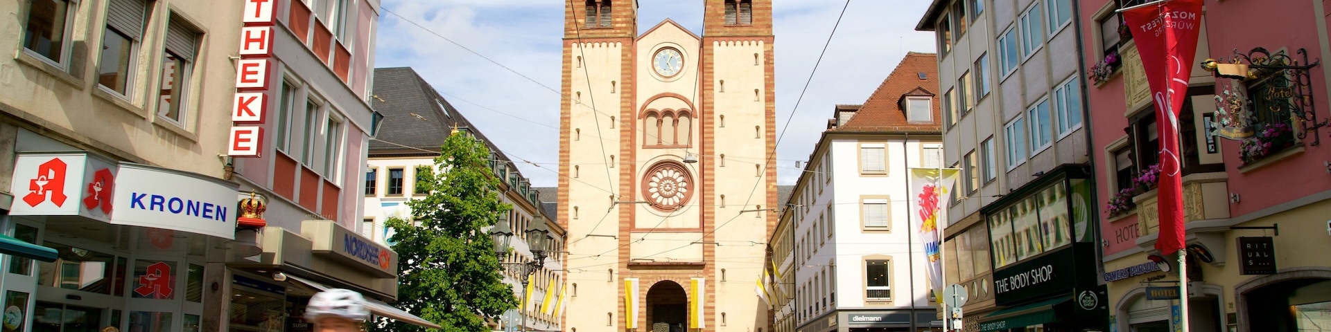 A bustling street with a prominent church tower, shops, and pedestrians.