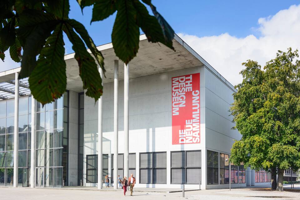 A modern building with a large glass facade and a prominent red banner reading "THE NEW SAMMLUNG."