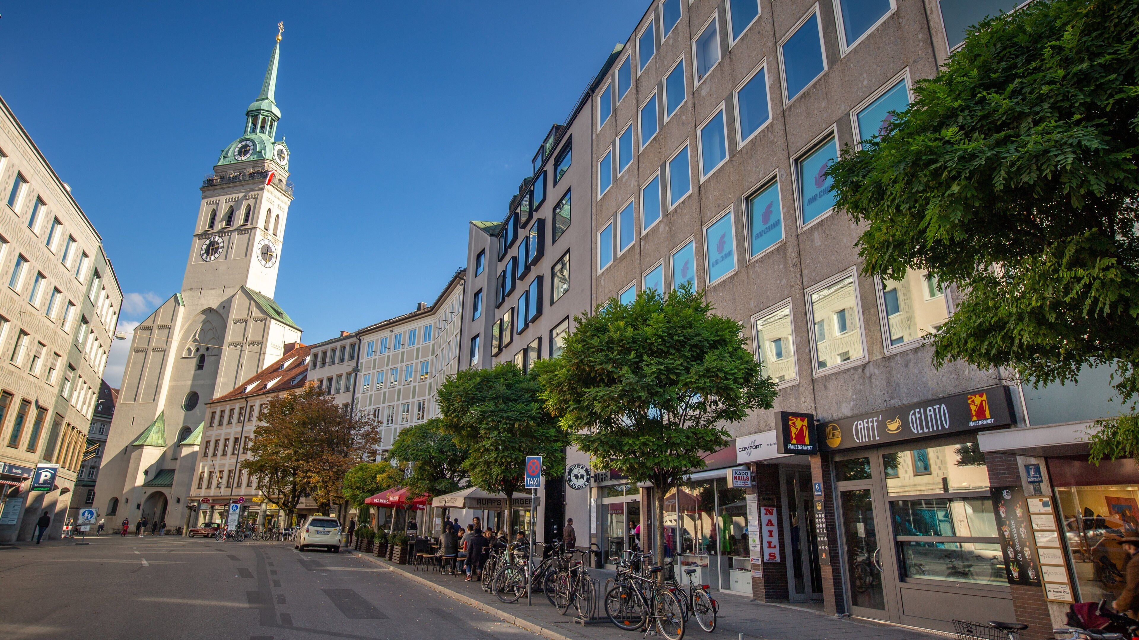 Una calle urbana con edificios históricos, una torre del reloj y diversas tiendas.