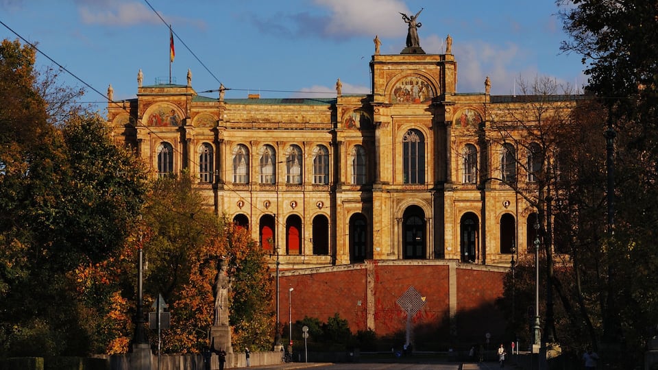 A historic building with ornate architecture, including a statue on the roof and a mural on the facade.