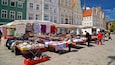 A bustling outdoor market with various stalls selling clothes and shoes.