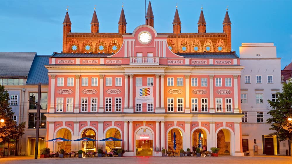 Ein historisches Gebäude mit einem Uhrturm, Rundbogenfenstern und einem zentralen Eingang.