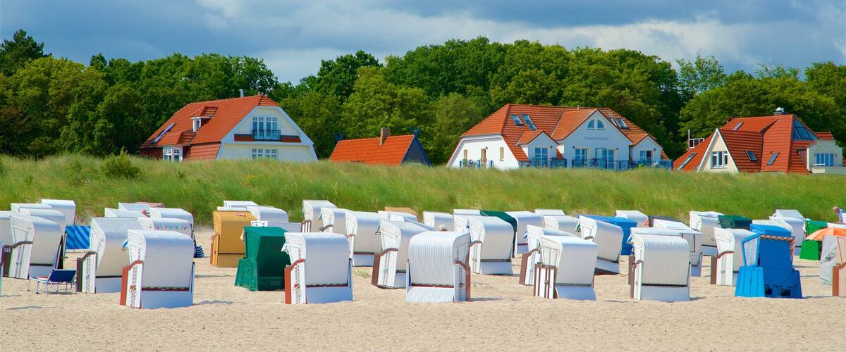 Beach chairs and houses on a sandy beach with a cloudy sky.