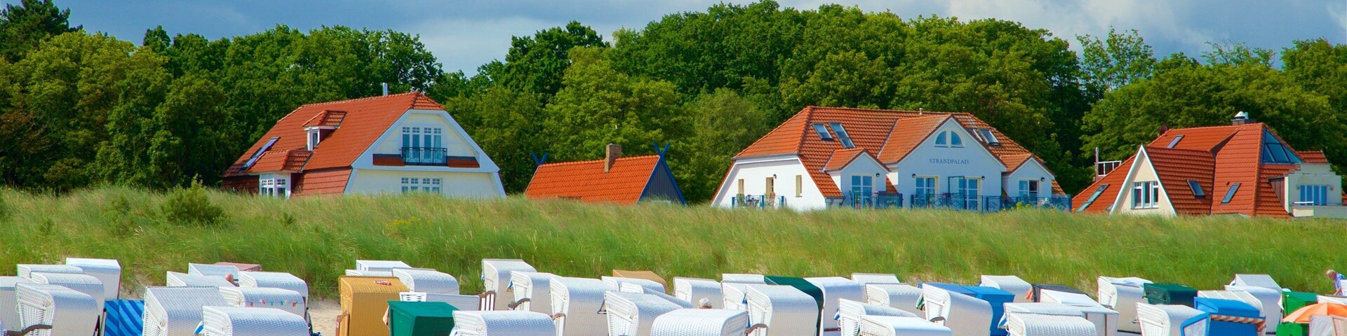 Beach chairs and houses on a sandy beach with a cloudy sky.