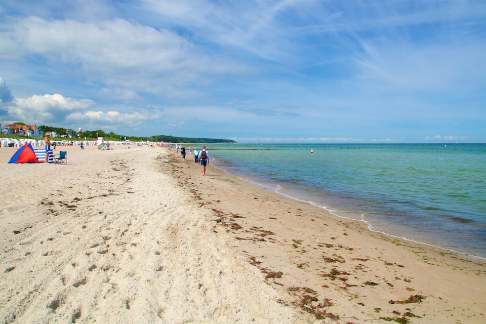 A sandy beach with footprints, a tent, and a clear blue sky.