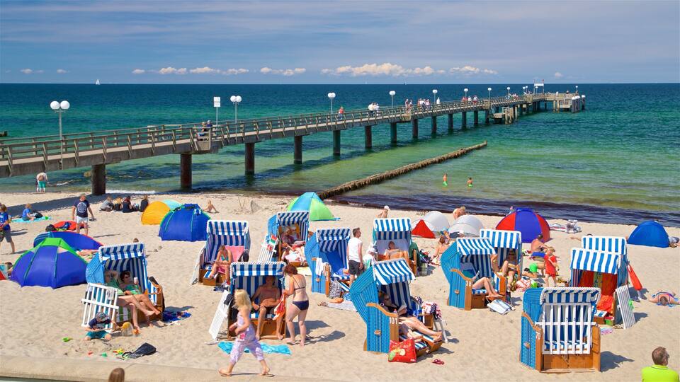 A beach with beach chairs, umbrellas, and a pier extending into the ocean.