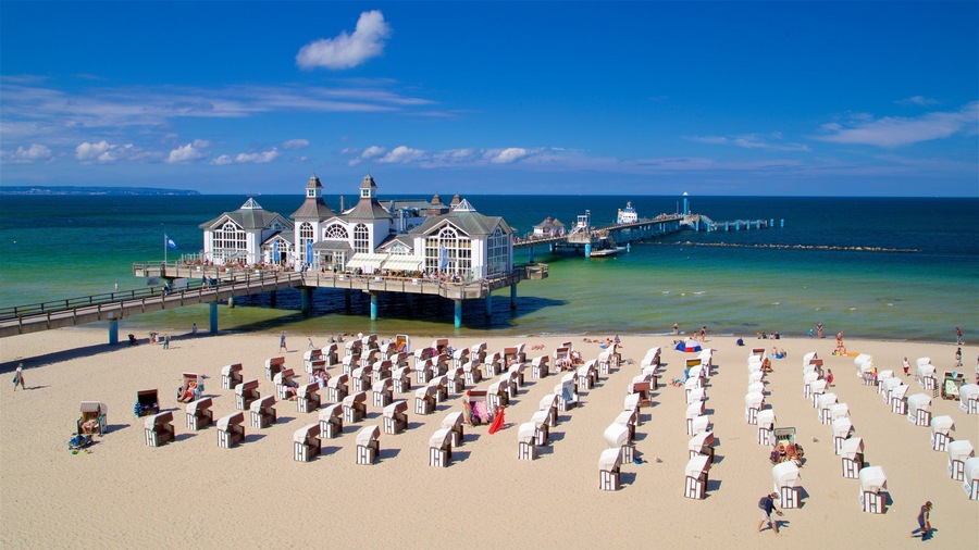 Une plage bordée de rangées de cabanes et d’une jetée qui s’avance dans l’océan.