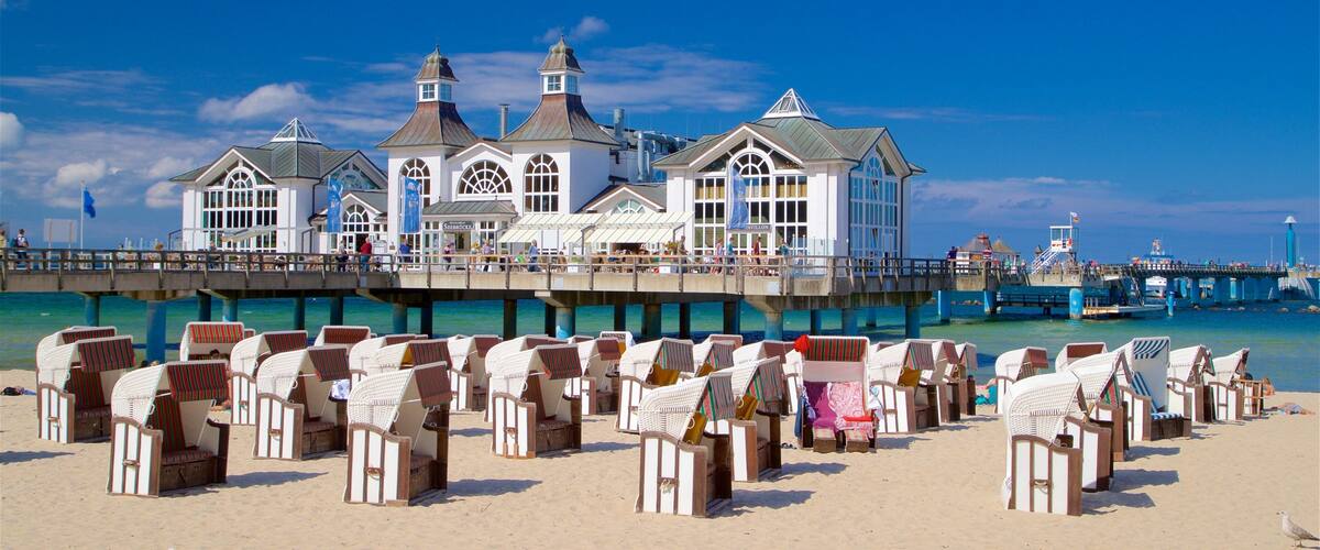 A pier with beach chairs and a white building with multiple windows and a flag.